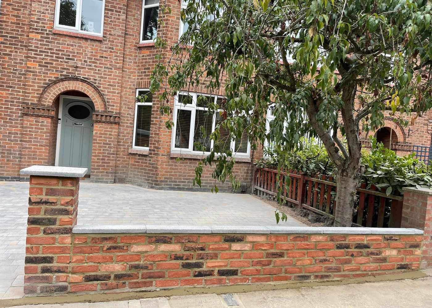 Block paved driveway to a red brick York house with new front wall